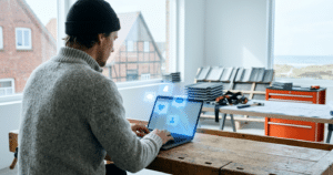 Social Media Marketing für Dachdecker: Laptop mit leuchtenden Social Media Icons und Dach-Elementen im Hintergrund