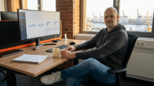 Solopreneur Office Schreibtisch mit Doppel-Monitor, Notizblock, Kaffeetasse und professioneller Tech-Peripherie auf Holz
